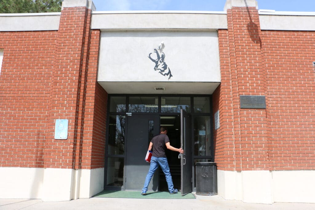 A male student walking into a school front door