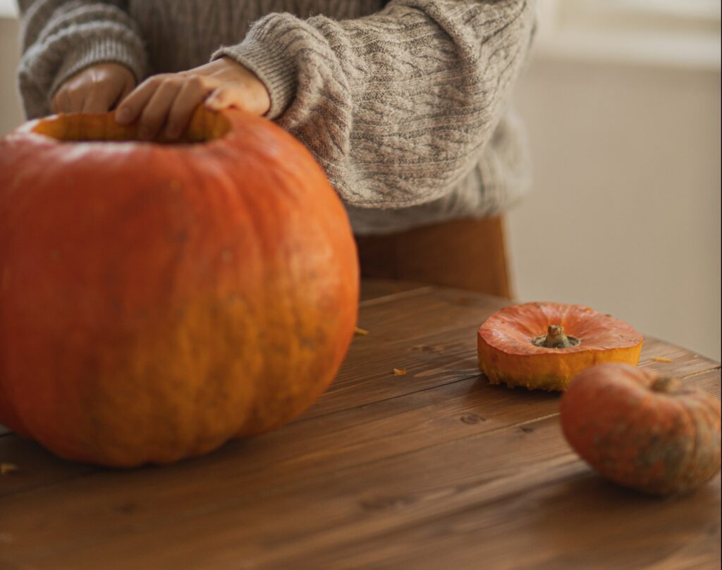 A woman carving a pumpkin on a table. 