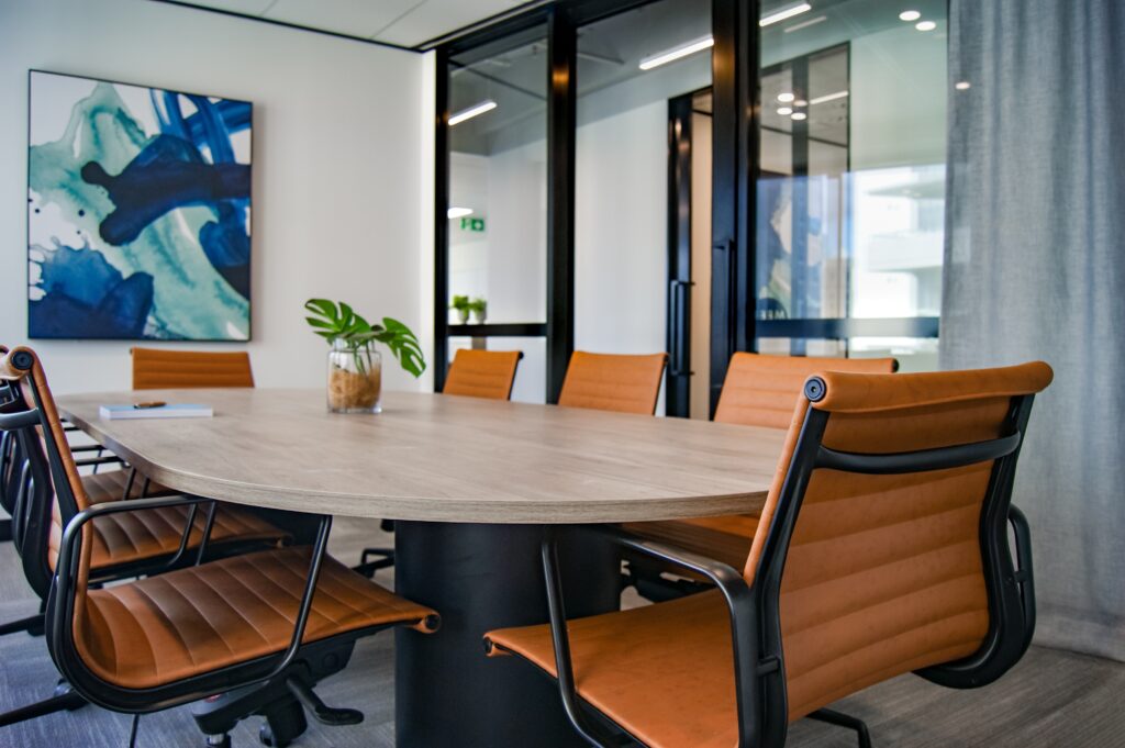 A modern conference room with an oval table and tan leather chairs. 