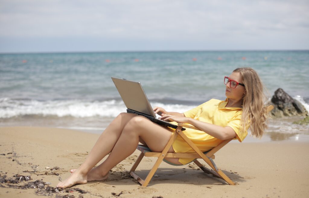 Woman working on a laptop at the beach.